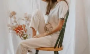 Woman sitting in a chair wearing Athflow outfit. Simple white t-shirt and beige cropped pants.