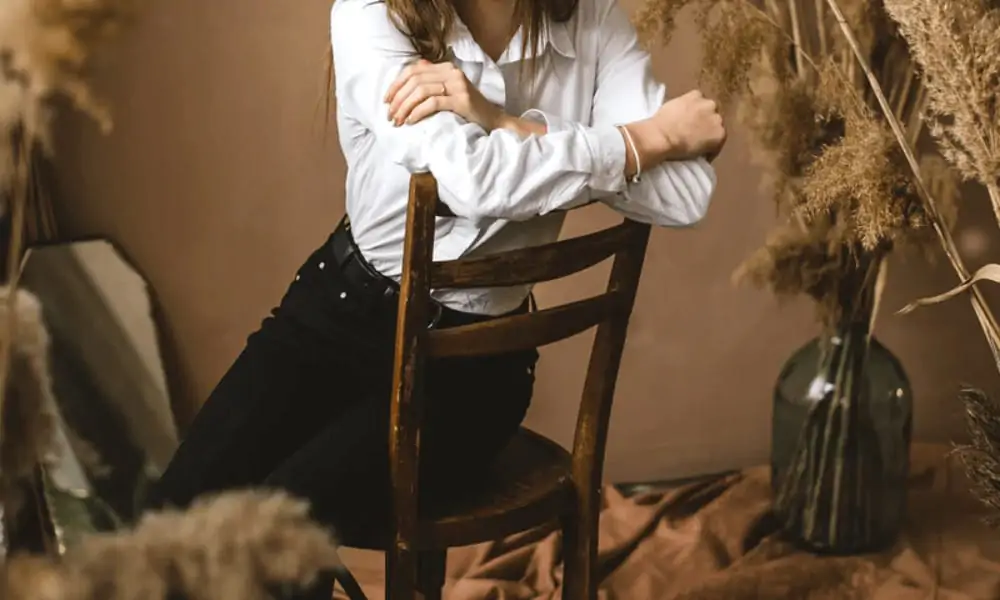 A woman wears a timeless outfit consisting of a white button-up and black jeans. 