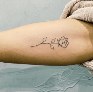 fine line flower tattoo on woman's forearm
